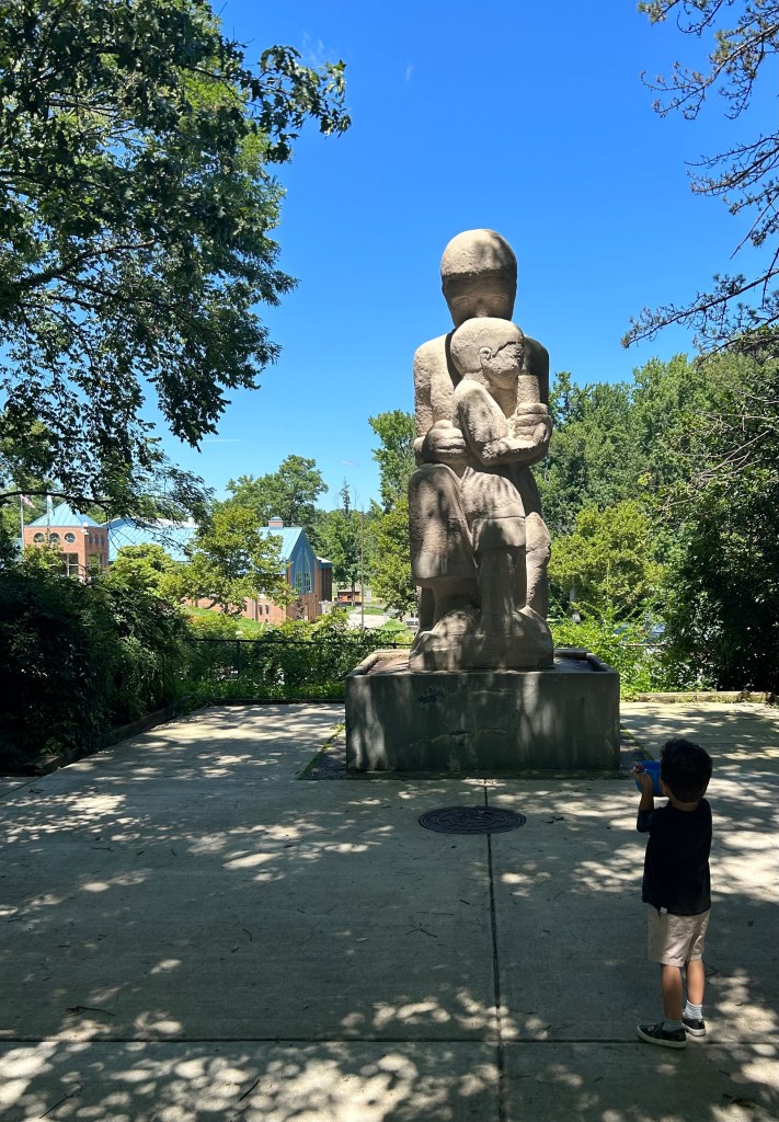 Statue of person and child and son looking at it in Greenbelt, MD