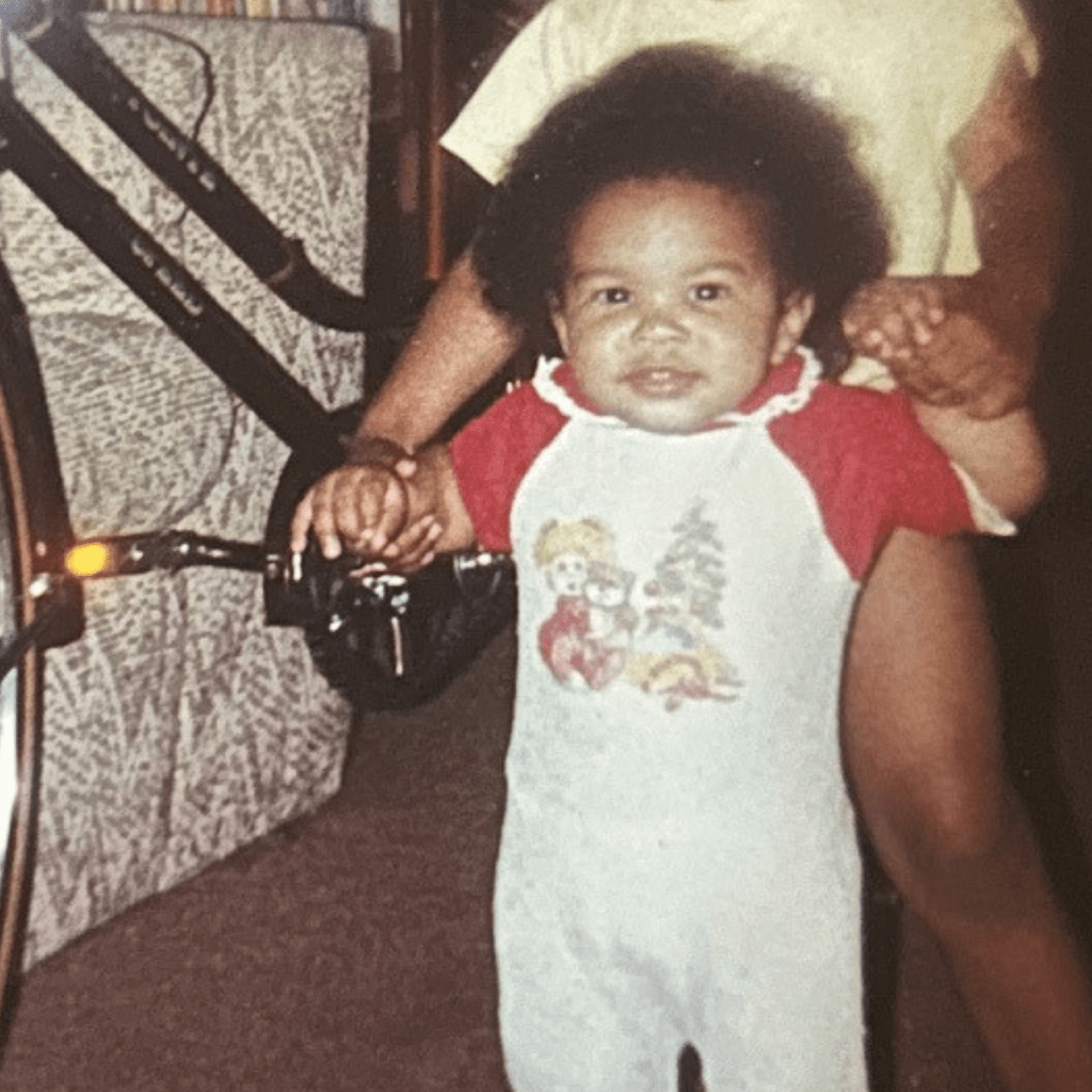 baby in front of bike with big hair and 80's onsie